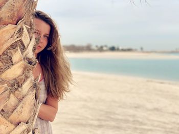 Woman standing at beach against sky