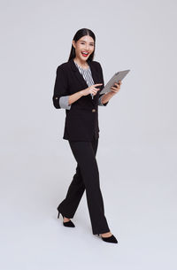 Portrait of young woman standing against white background