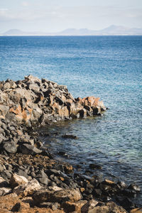 Scenic view of rocks in sea against sky in lanzarote 