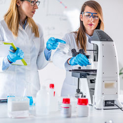 Female scientists examining chemical in laboratory