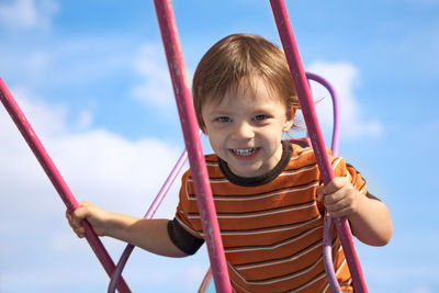 Portrait of cute boy smiling in playground against sky
