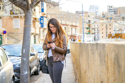 Woman using mobile phone in city