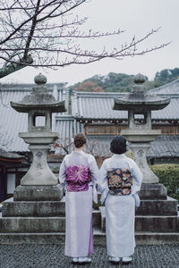 Rear view of people outside temple against building