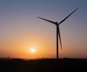 Silhouette windmills against sky during sunset