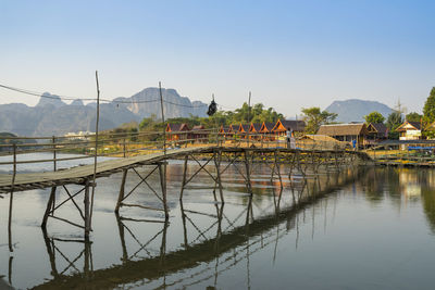 Bridge over river by buildings against sky