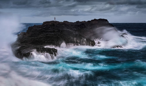 Scenic view of waterfall in sea against sky