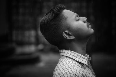 Side view of young man with eyes closed standing outdoors