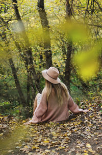 Rear view of woman sitting in forest