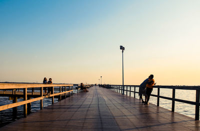 Man on pier over sea against clear sky
