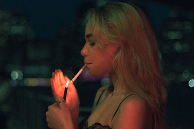 Portrait of young woman blowing bubbles at night