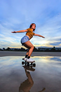 Asian women playing surf skate or skates board outdoors on beautiful summer day. 