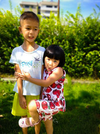 Portrait of girl embracing brother at park