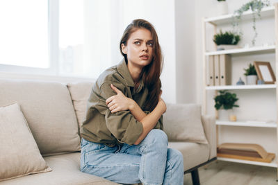 Portrait of young woman sitting on sofa at home