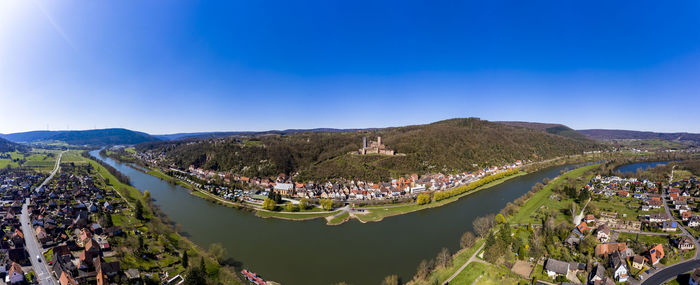 High angle view of river amidst cityscape against clear blue sky