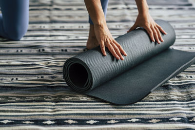 Low section of woman rolling exercise mat