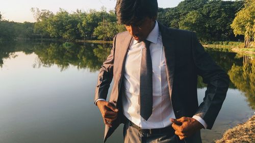 Man wearing suit standing by lake