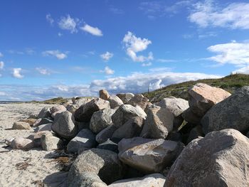 Scenic view of rocky beach against cloudy sky