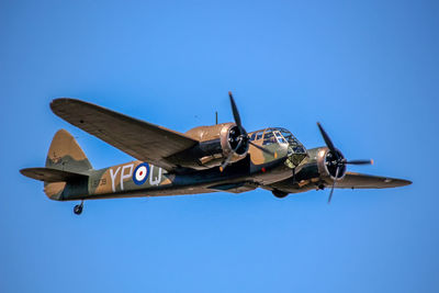 Low angle view of airplane flying against clear blue sky