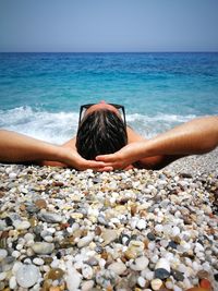 Woman with arms raised on beach against clear sky