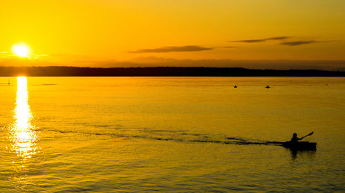 Silhouette man in sea against sky during sunset