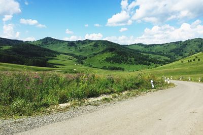 Scenic view of road by mountains against sky