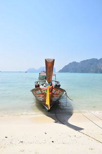 Boat moored on beach against clear sky