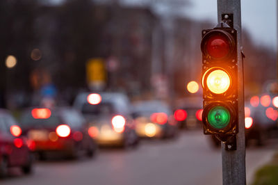 City crossing with a semaphore on blurred background with cars in the evening streets, orange light