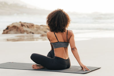 Rear view of woman sitting on beach