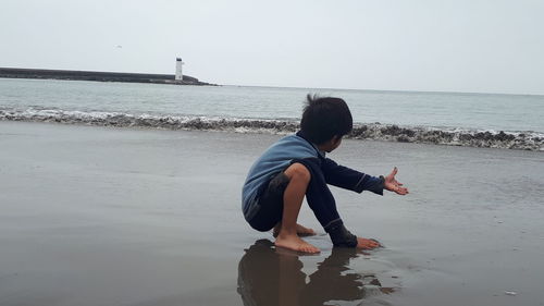 Man on beach against clear sky