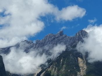 Low angle view of clouds over mountain against sky