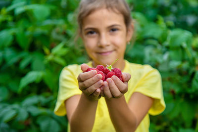 Portrait of smiling girl holding raspberries