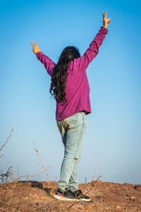 Isolated young girl standing at mountain top with blue sky from flat angle