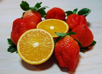 Close-up of sliced orange with strawberries on table