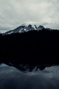 Scenic view of lake by snowcapped mountains against sky
