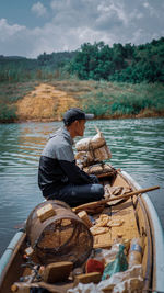 Side view of man sitting on boat in lake