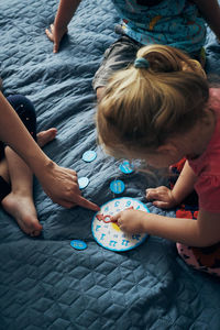 High angle view of people sitting by toy clock on bed