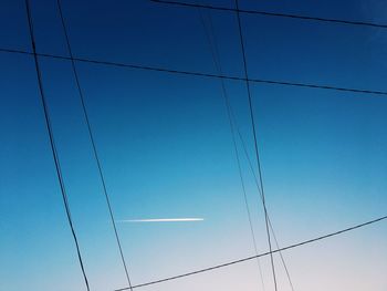 Low angle view of power lines against clear blue sky