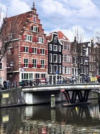 Canal by buildings in city against sky