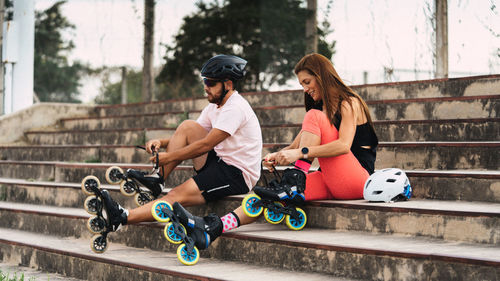 Couple wearing inline skates while sitting on steps outdoors