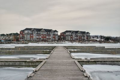 Houses by buildings against sky in city during winter