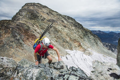 Man standing on rock by mountain against sky