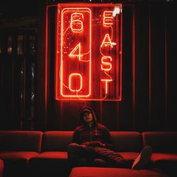 Full length of woman sitting in illuminated bar