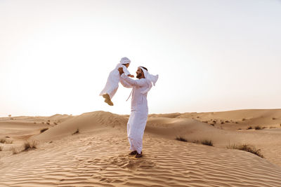 Smiling father and son enjoying while standing in desert