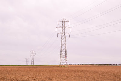 Low angle view of electricity pylon on field against sky