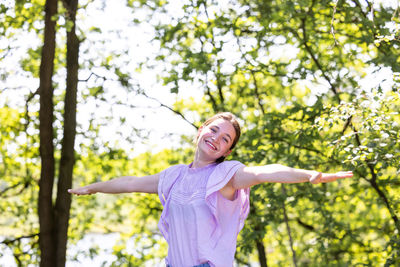 Young woman standing against trees