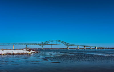 Bridge over sea against clear blue sky