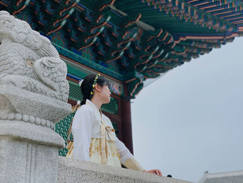 Low angle view of woman looking away while standing at temple