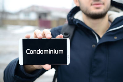 Man holding mobile phone with condominium text