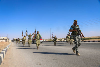 Full length of soldiers walking on road against sky