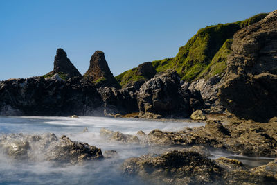 Scenic view of rocks in sea against clear sky